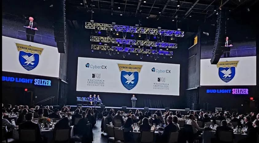 Sponsor logos on the ceremony screens above a seated ballroom audience.